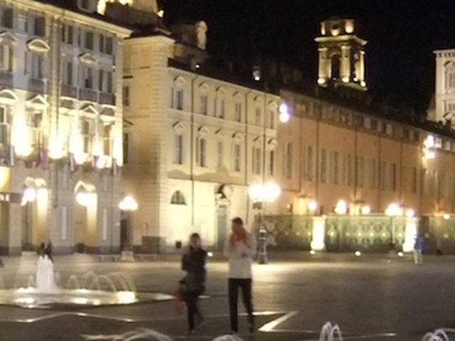 Piazza di Torino di notte con i palazzi illuminati e le fontane